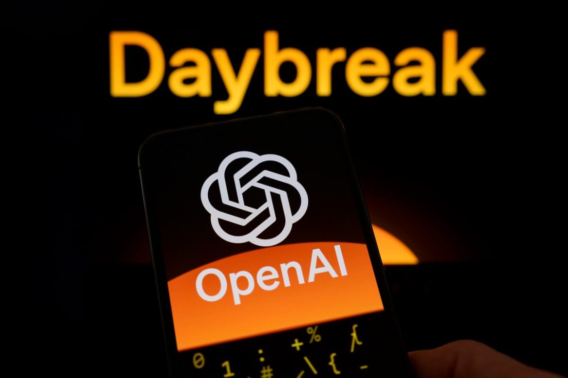 The OpenAI logo is displayed on a smartphone screen held in one hand, with the Daybreak visual in the background.